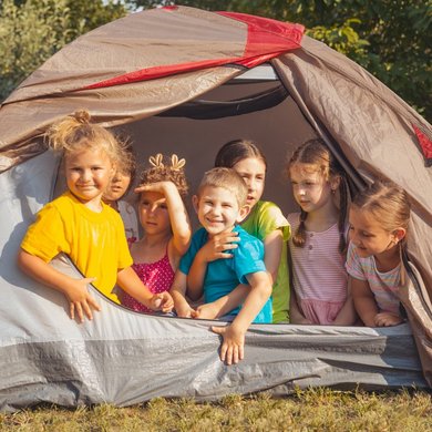 Kleine Kinder schauen aus einem Zelt