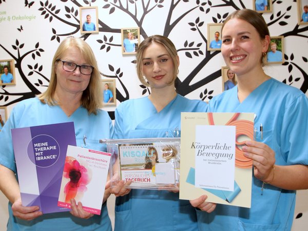 Drei Krankenschwestern halten Infomaterial hoch