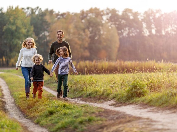 Mutter, Vater und ihre beiden Söhne laufen über einen Feldweg