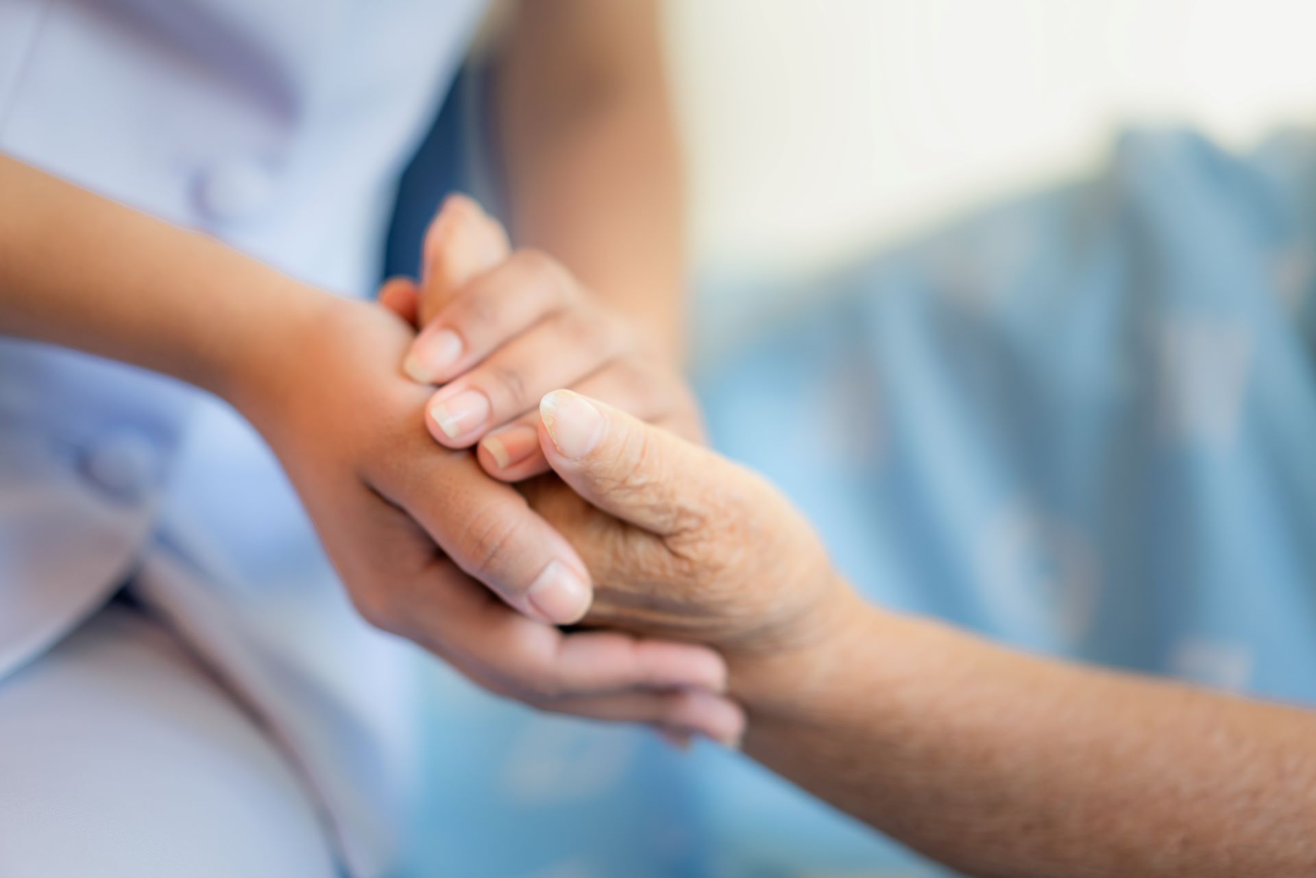 Eine Pflegekraft hält die Hand von einer Patientin